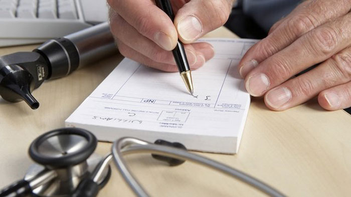 Image showing a notepad being filled-in a doctor using a black pen along with part of a stethoscope
